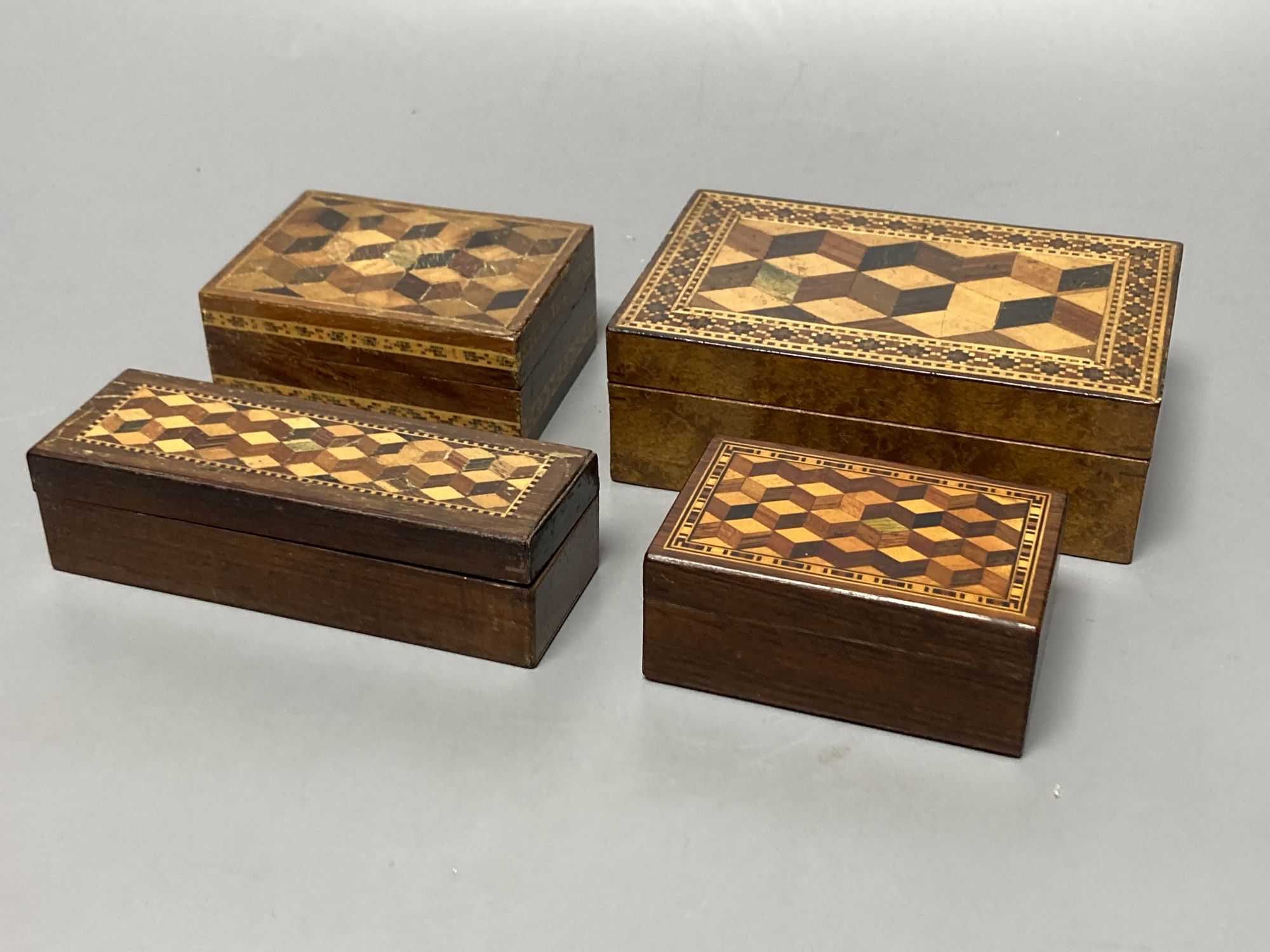 Four Tunbridge ware perspective cube marquetry small boxes, early 20th century, largest 12.2cm, one containing Goodall, London miniature playings cards (not checked if complete), 8.2cm and another with Thomas Barton inks